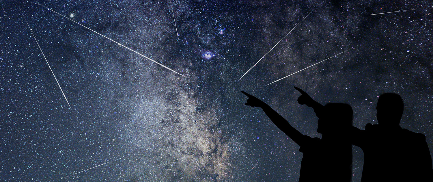 Un ciel avec des étoiles filantes et deux personnes silhouettées qui les regardent